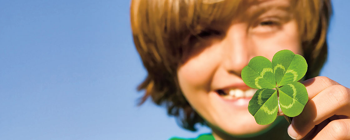 A boy holding a green leaf clover